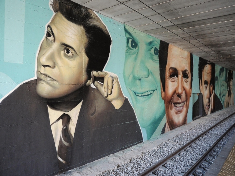 I volti di Massimo Troisi e Alighiero Noschese nella stazione della Circumvesuviana di San Giorgio a Cremano
